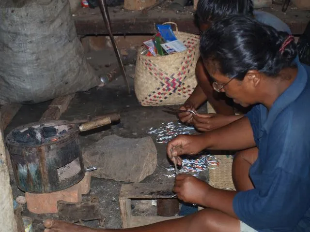 Artisane malgache confectionnant des bijoux traditionnels avec des perles colorées dans un atelier local