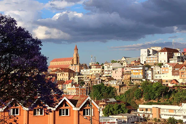 Paysage urbain Malgache avec cathédrale colorée et toits en pente sous ciel nuageux