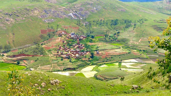 Paysage verdoyant de Madagascar montrant village traditionnel entouré de rizières en terrasses et collines boisées